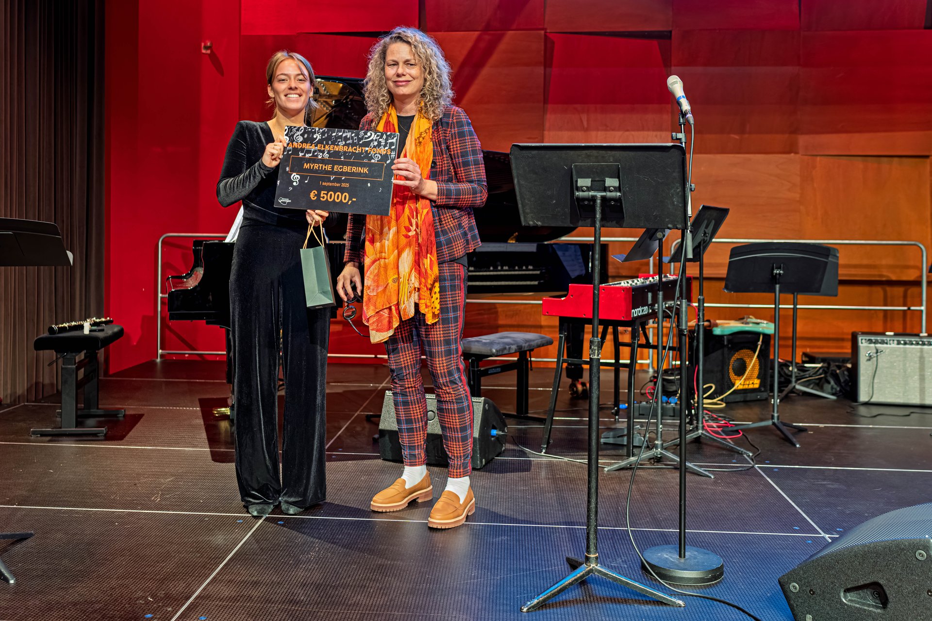 Hoboïst Myrthe Egberink (links) krijgt uit handen van cultuurwethouder Kirsten de Wrede een symbolische cheque voor de beurs vanuit het Andrea Elkenbrachtfonds overhandigd.  