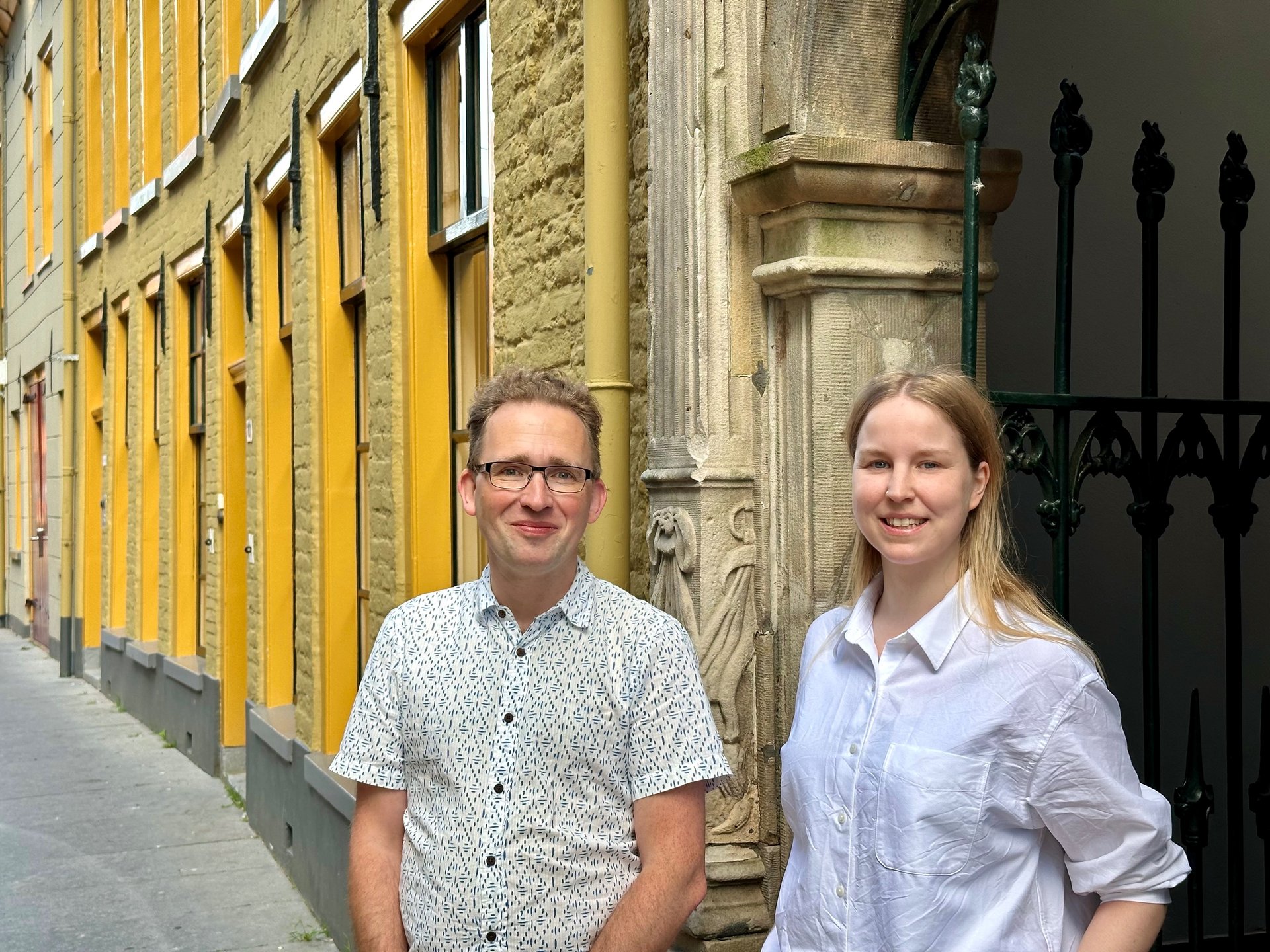 Erfgoedmedewerkers Esdert Glazenburg en Anna Bouman voor de toegangspoort van het Rode Weeshuis in Groningen.